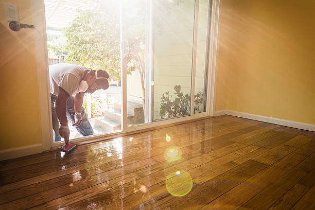 Homme qui applique du vitrificateur sur son parquet en bois